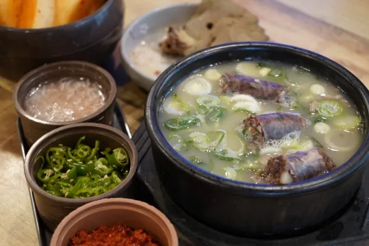검은 뚝배기 순대국밥 근접 — 새우젓·고추·다대기